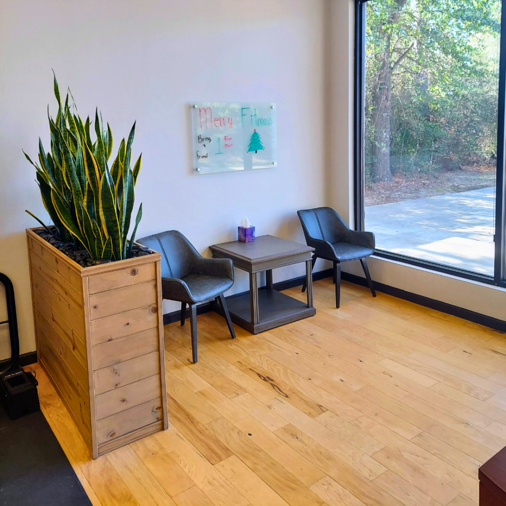 Image of a bright and inviting gym reception area with a desk and chairs. Snake plants are visible in the background.